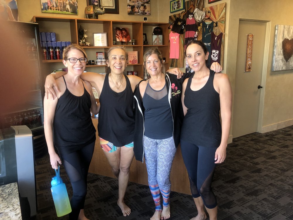Ann Marie Palma with students smiling together inside Bikram Yoga El Paseo studio.