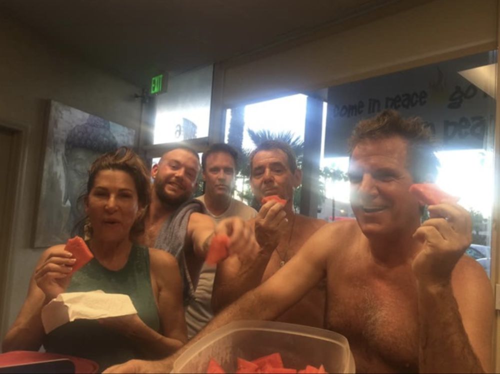 Group of Bikram Yoga El Paseo students smiling and eating watermelon together after class.