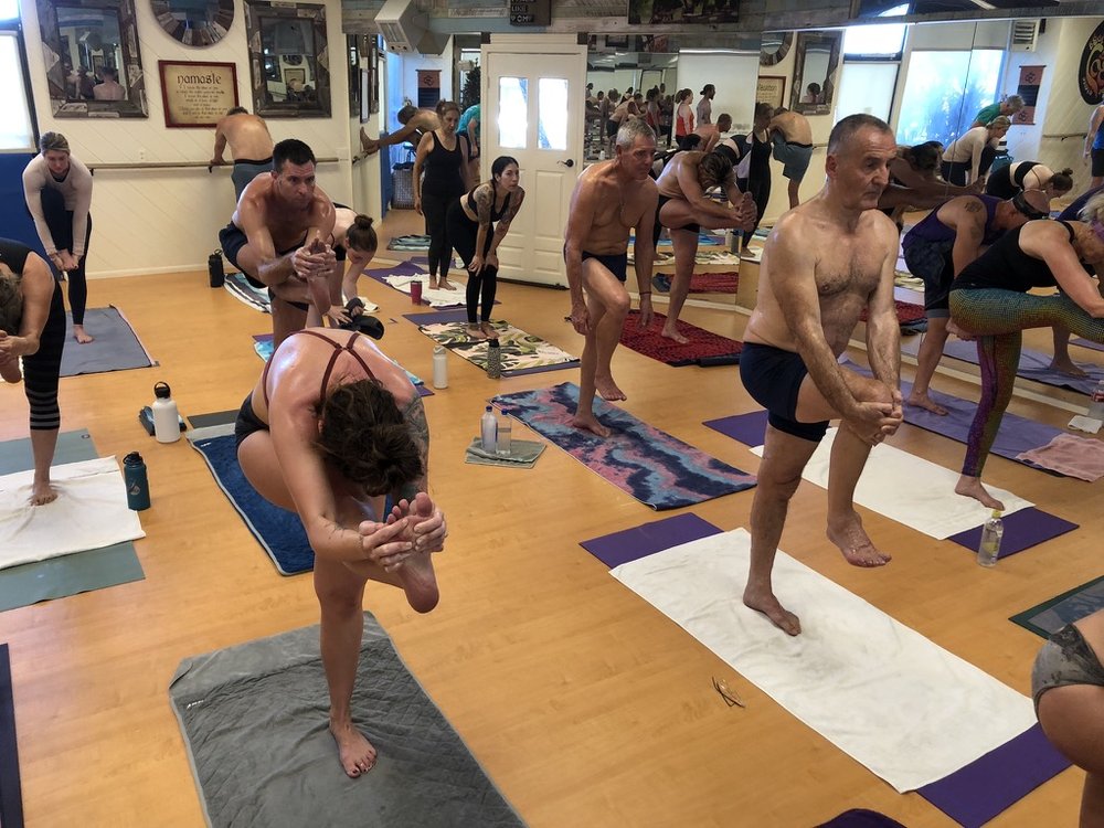 Bikram Yoga El Paseo students balancing in Dandayamana Janushirasana
 (standing head-to-knee pose) during class.