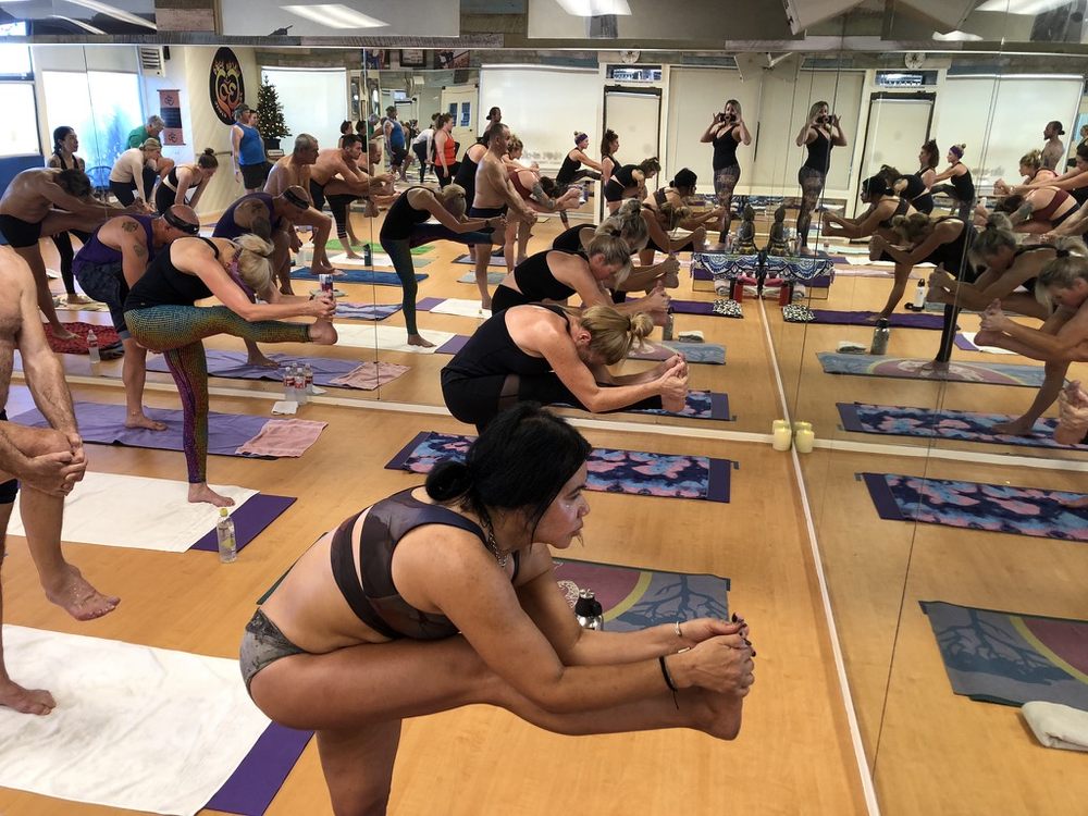 Bikram Yoga El Paseo students balancing in Dandayamana Janushirasana
 (standing head-to-knee pose) during class.