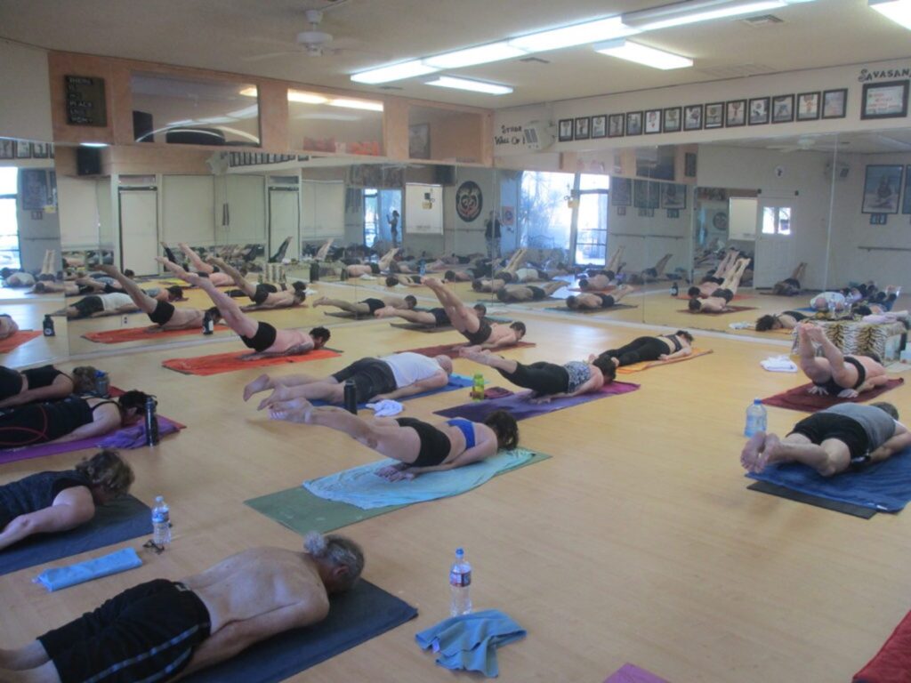 Hot yoga students lifting legs in Locust Pose (Salabhasana) at Bikram Yoga El Paseo.